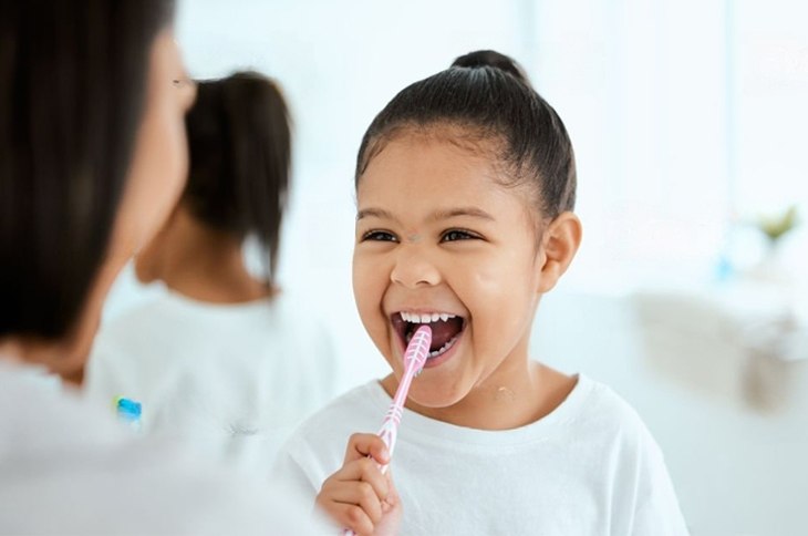 Mother helping young girl brush her teeth l Children's Dentistry Burien WA