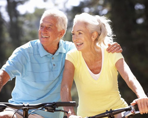 Older couple riding bikes in forest l Dental implants burien WA