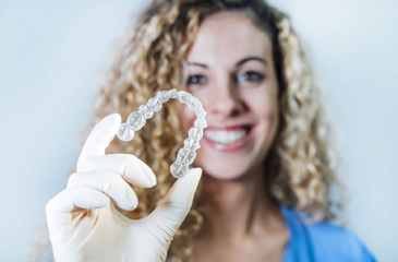 woman holding a clear plastic aligner I orthodontics burien WA